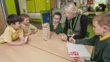 A teacher sat at a table with some young school children