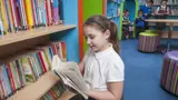 A young girl reading a book in the school library