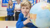 A young boy in his school uniform holding a globe
