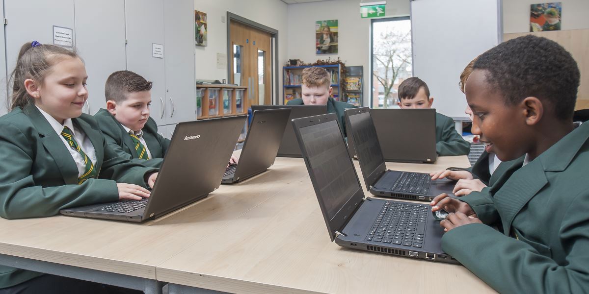 Children in a classroom using laptops